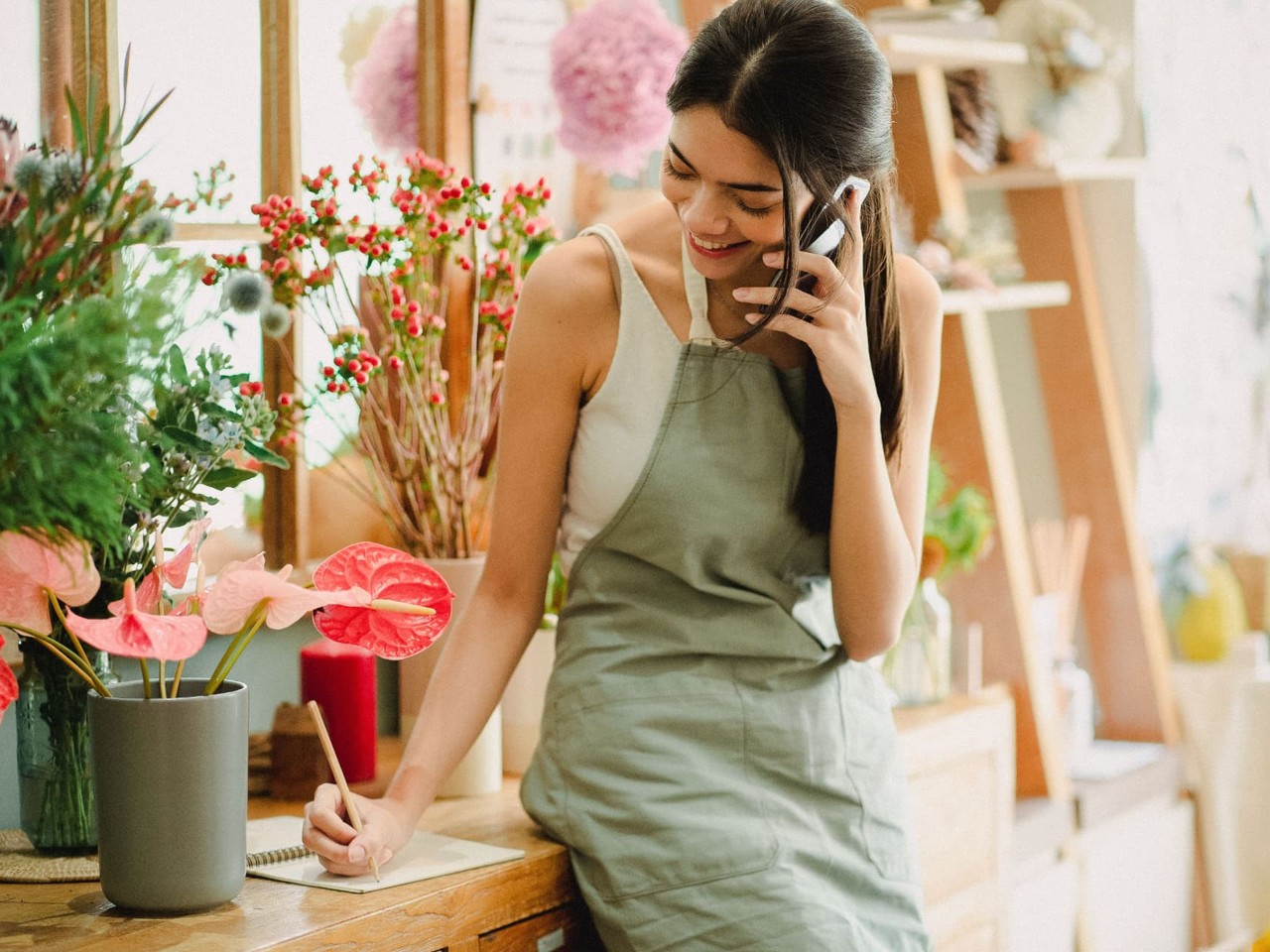 A florist shop owner taking an order by phone among flowers and plants